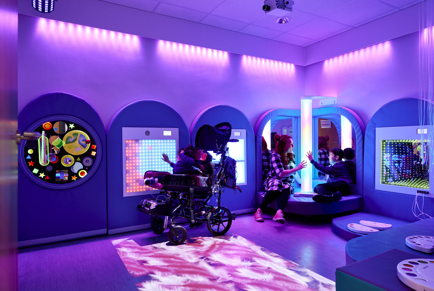 Children exploring illuminated panels and a bubble tube in a SpaceKraft sensory room